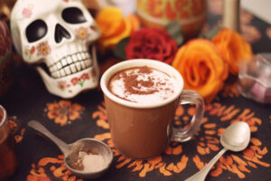 Cup of hot cocoa surrounded by Dia de los Muertos decorations