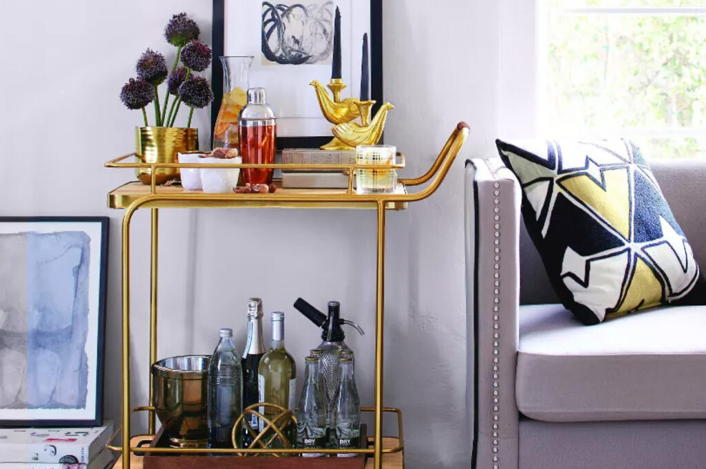 A gold, metal bar cart situated next to a couch
