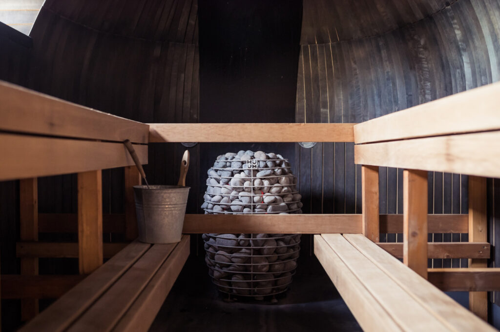 View inside of a sauna with benches and hot rocks.