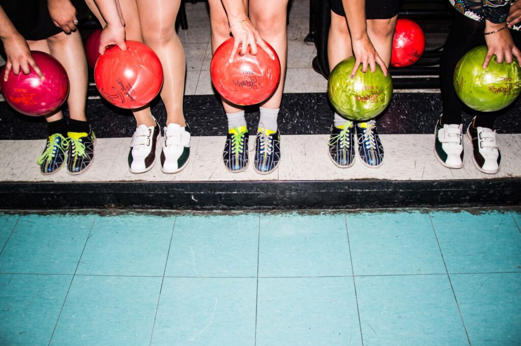 Group of bowlers with bowling balls in hand.